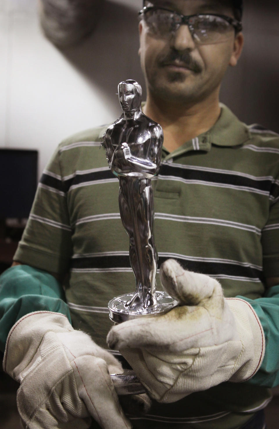 CHICAGO, IL - FEBRUARY 09: Martin Vega inspects an Oscar statuette he cast at R.S. Owens & Company February 9, 2012 in Chicago, Illinois. R.S. Owens manufactures the Oscar statuettes which are presented at the annual Academy Awards by the Academy of Motion Picture Arts and Sciences. After the theft of the statuettes prior to the 2000 Academy Awards the company began casting the statuettes one year in advance of the show. (Photo by Scott Olson/Getty Images)