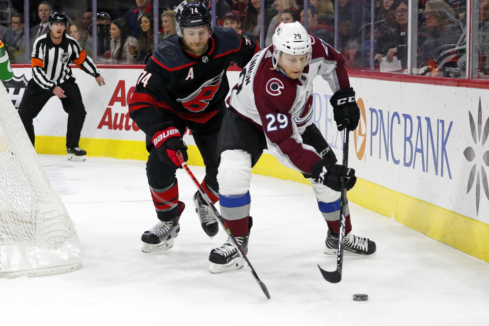 Colorado Avalanche's Nathan MacKinnon (29) vies with Carolina Hurricanes' Jaccob Slavin (74) for the puck during the first period of an NHL hockey game in Raleigh, N.C., Friday, Feb. 28, 2020. (AP Photo/Karl B DeBlaker)