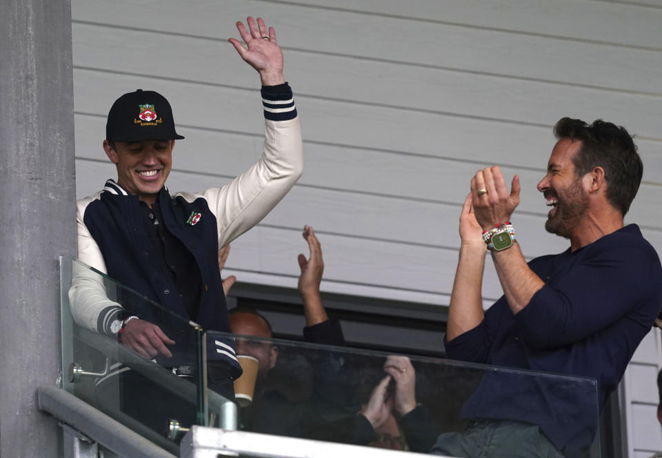 Wrexham co-owners Rob McElhenney, left, and Ryan Reynolds in the stands during the National League soccer match between Wrexham and Boreham Wood at The Racecourse Ground, in Wrexham, Wales, Saturday April 22, 2023. (Martin Rickett/PA via AP)