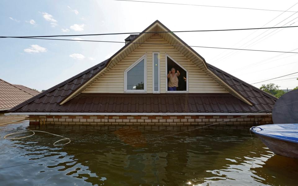 A woman who refuses to be evacuated from a flooded house gestures towards the rescuers following the collapse of the Nova Kakhovka dam - ALEXANDER ERMOCHENKO/REUTERS