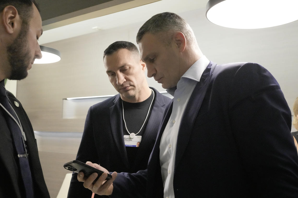 Kyiv Mayor Vitali Klitschko, right, watches his phone beside his brother Wladimir Klitschko at the World Economic Forum in Davos, Switzerland, after a helicopter crash in Ukraine, where Minister of Internal Affairs Denys Monastyrsky died among others on Wednesday, Jan. 18, 2023. The annual meeting of the World Economic Forum is taking place in Davos from Jan. 16 until Jan. 20, 2023. (AP Photo/Markus Schreiber)