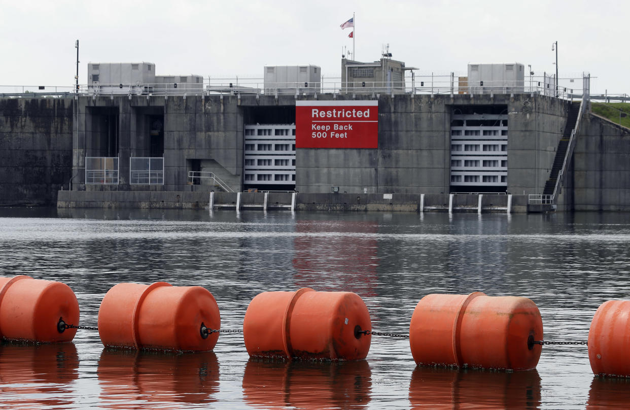 Orange buoys in front of a dam with sign that reads: Restricted, keep back 500 feet.