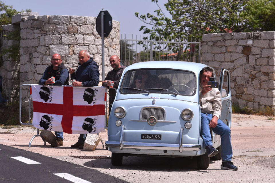 <p>Locals show their attachment to their land. Some tifosi here, in a typical Italian car and holding a Sardinian flag during Stage 2, Olbia-Tortoli (221km). </p>