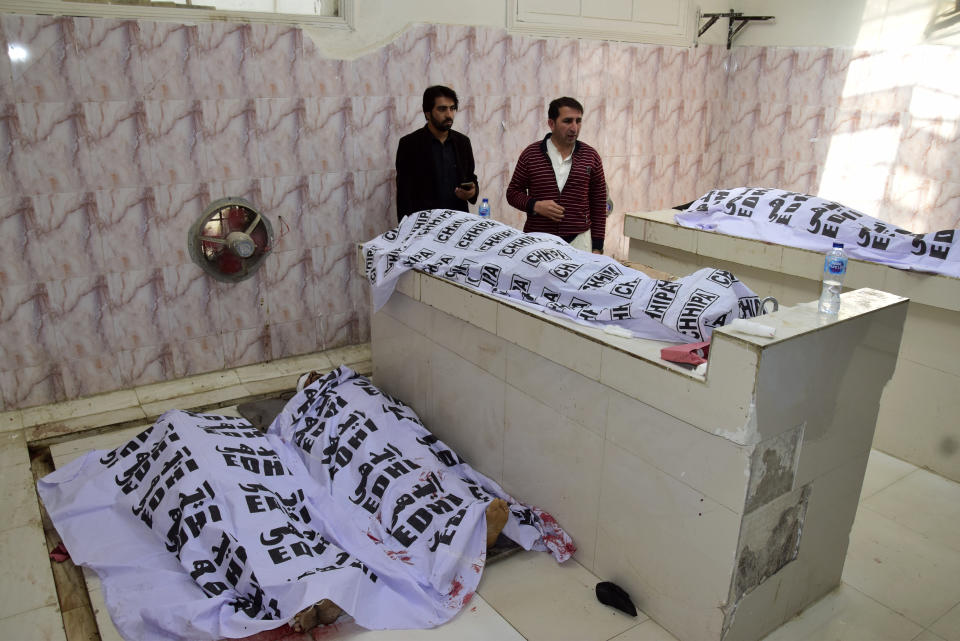 People stand by bodies of victims as they try to identify, following Pashin district's bomb blast, at a morgue in a hospital in Quetta, Pakistan, Wednesday, Feb. 7, 2024. A pair of bombings at the election offices of a political party and an independent candidate in southwest Pakistan killed some people and wounded more, officials said Wednesday, the day before parliamentary elections are to be held. (AP Photo/Arshad Butt)