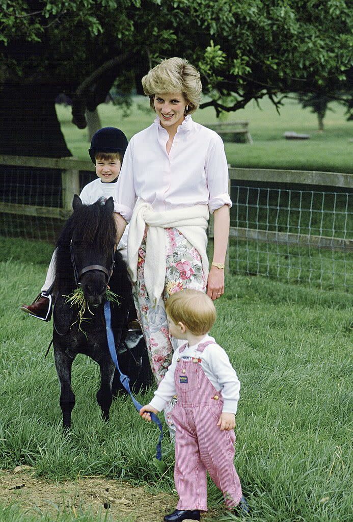 <p>Princess Diana plays with her sons, William and Harry, on the grounds of Highgrove in 1986. William is riding a pony.</p>