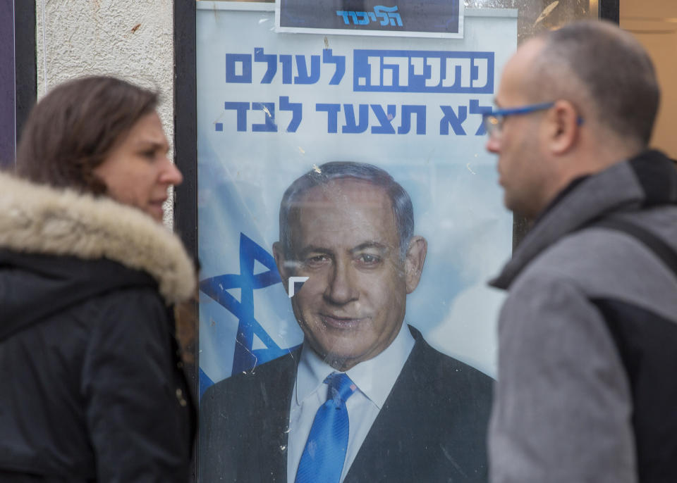 People look at a poster of Israel Prime Minister and governing Likud party leader Benjamin Netanyahu at a voting center in the northern Israeli city of Hadera, Thursday, Dec. 26, 2019. Israel's governing Likud party was holding primaries on Thursday, in the first serious internal challenge to Israeli Prime Minister Benjamin Netanyahu in his more than a decade in power. (AP Photo/Ariel Schalit)