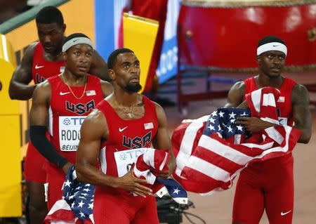 Tyson Gay of the U.S. (2ndR) and his teammates Mike Rodgers (2ndL), Trayvon Bromell (R) and Justlin Gatlin (L) fold up their national flags after learning of their disqualification in the men's 4 x 100 metres relay final during the 15th IAAF Championships at the National Stadium in Beijing, China August 29, 2015. REUTERS/David Gray