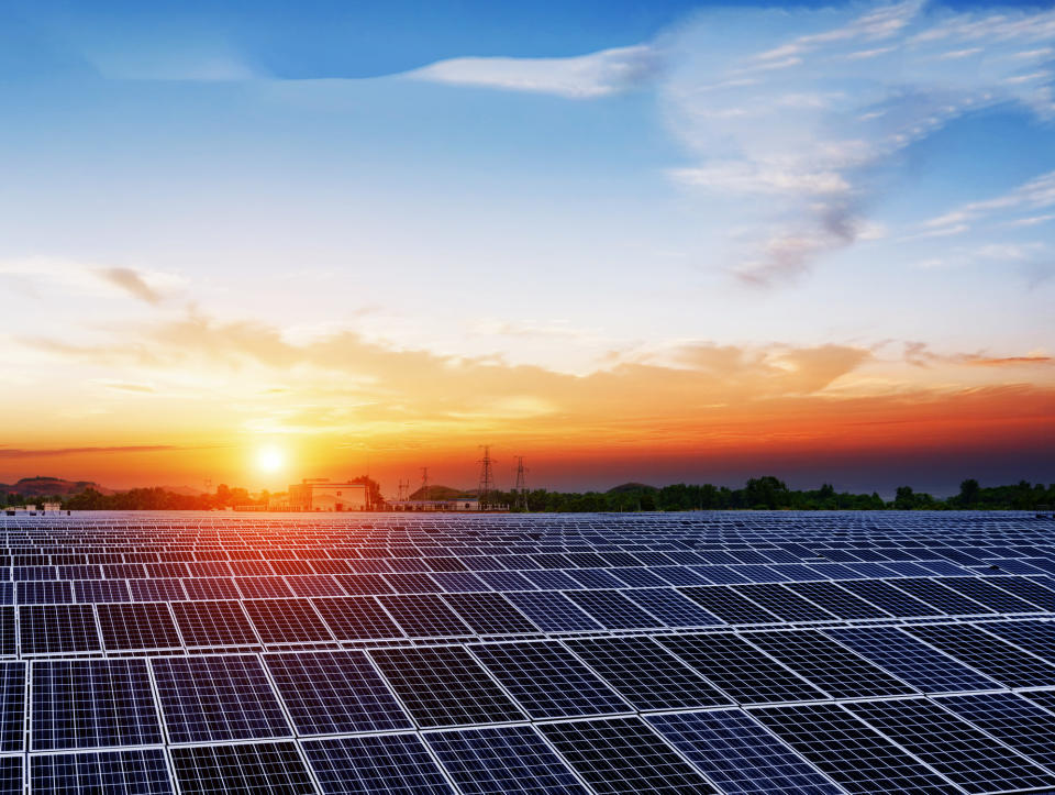 Solar panels under a blue sky at sunset.