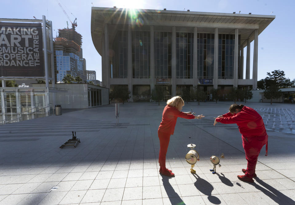 Members of the Bob Baker Marionette Theater keep their social distance as they practice on the Dorothy Chandler Pavilion's courtyard in Los Angeles Friday, Feb. 5, 2021. Due to the coronavirus pandemic, the Bob Baker Marionettes have gone digital worldwide, as the public can now tune in for a personalized Zoom puppet experience. (AP Photo/Damian Dovarganes)