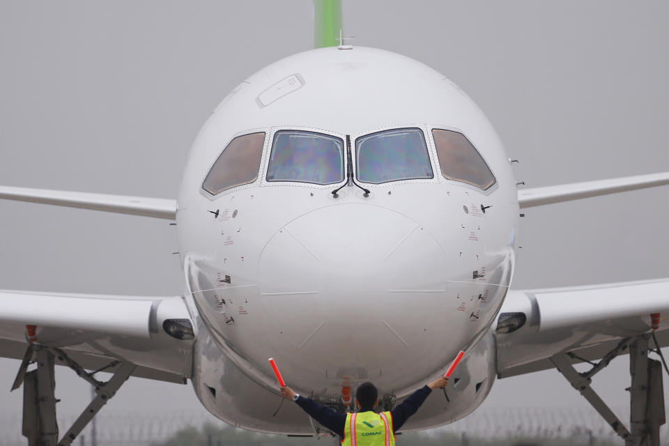 A member of staff gives signal in front of China's home-grown C919 passenger jet after it landed on its maiden flight at the Pudong International Airport in Shanghai, Friday, May 5, 2017. The first large Chinese-made passenger jetliner C919 took off Friday on its maiden flight, a symbolic milestone in China's long-term goal to break into the Western-dominated aircraft market. (Aly Song/Pool Photo via AP)