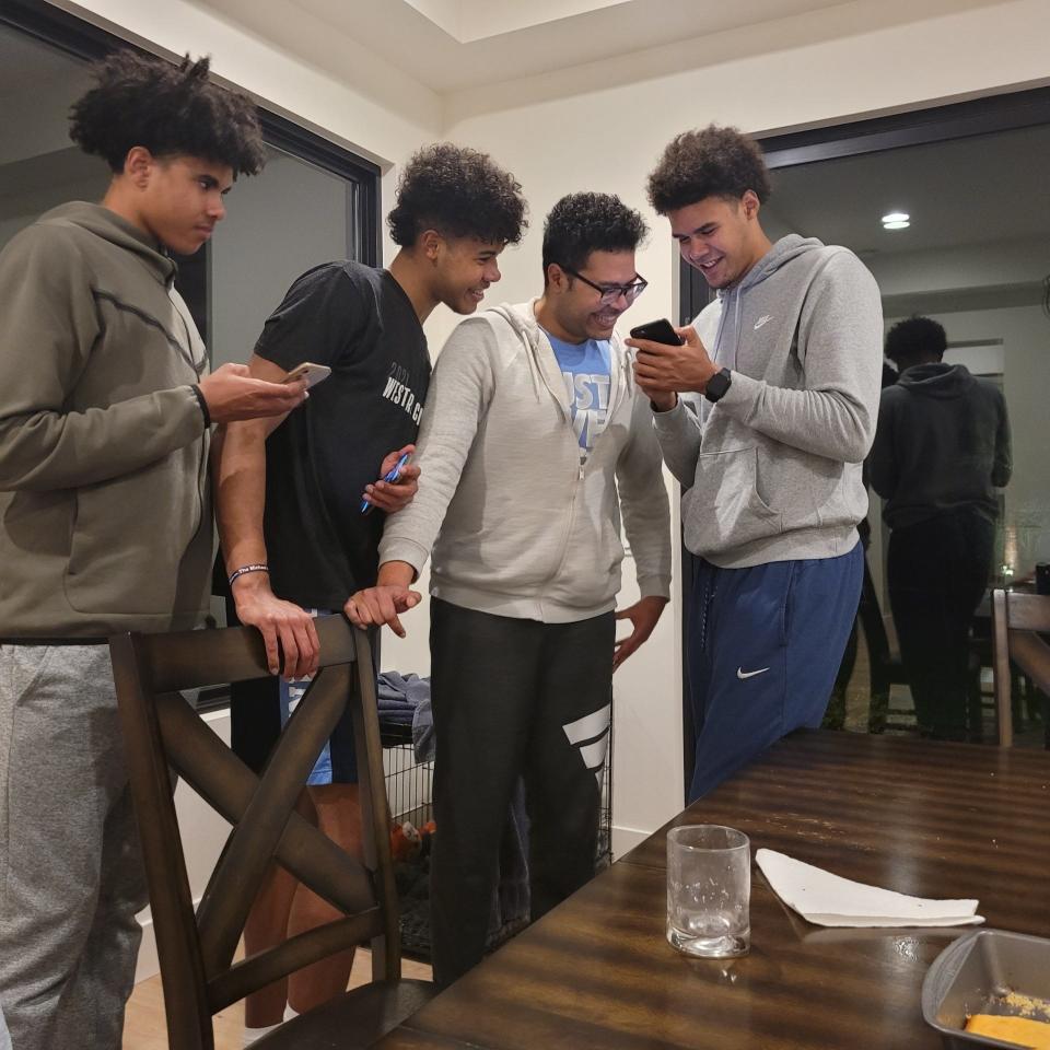 Brothers (left to right) Braylon Johnson, Puff Johnson, Aaron Johnson, and Cameron Johnson stand together amused by what's on Cameron's cell phone.