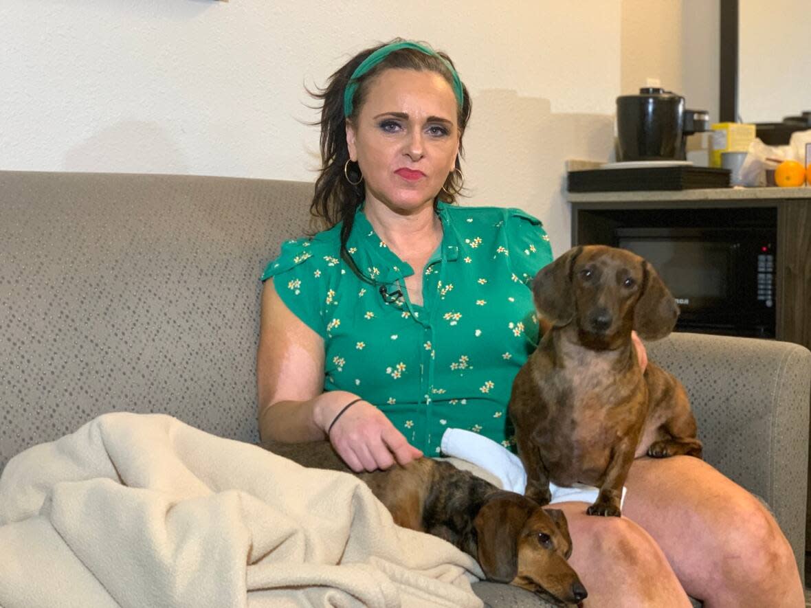 Lisa Dewitt sits with her dogs in a hotel room, where she's been living since she was evacuated from her apartment last month due to a fire. (Taryn Grant/CBC - image credit)