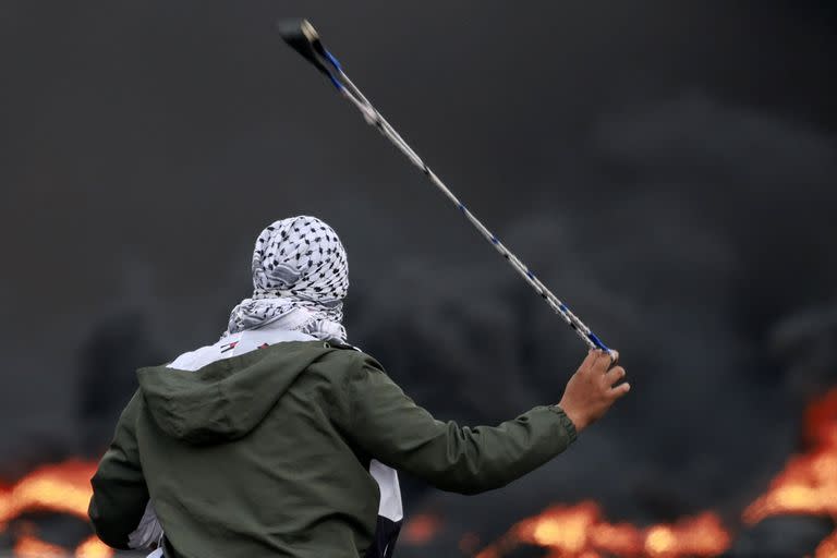 Un palestino lanza piedras a las fuerzas israelíes durante una manifestación contra los bombardeos isralíes en la franja de Gaza, en la ciudad de Ramala, en la Cisjordania ocupada, el 11 de octubre de 2023.  (Foto de Jaafar ASHTIYEH / AFP)