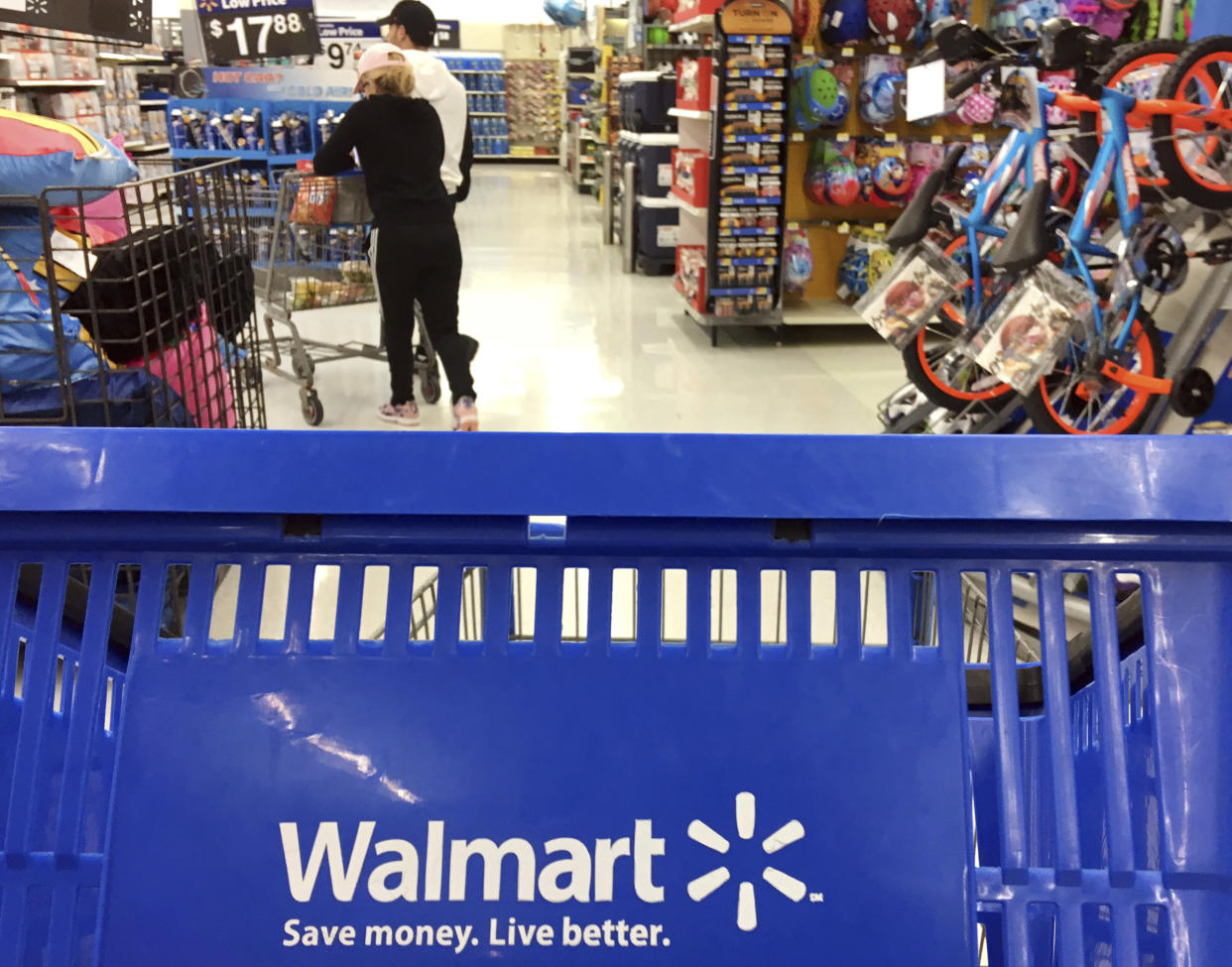 FILE - In this June 5, 2017, file photo, customers shop for food at Walmart in Salem, N.H. Walmart says it will no longer sell firearms and ammunition to people younger than 21. The retailer's new policy comes after Dick's Sporting Goods announced earlier Wednesday, Feb. 28, 2018, that it would restrict the sale of firearms to those under 21 years old. It didn't mention ammunition. Walmart says the decision came after a review of its firearm sales policy in light of the mass shooting at a high school in Parkland, Florida. (AP Photo/Elise Amendola, File)