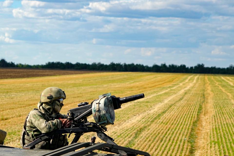 A Russian soldier atop of a military truck guards an area as farmers of the Voznesenka-Agro farm harvest with their combine in a wheat field not far from Melitopol, south Ukraine, Thursday, July 14, 2022.