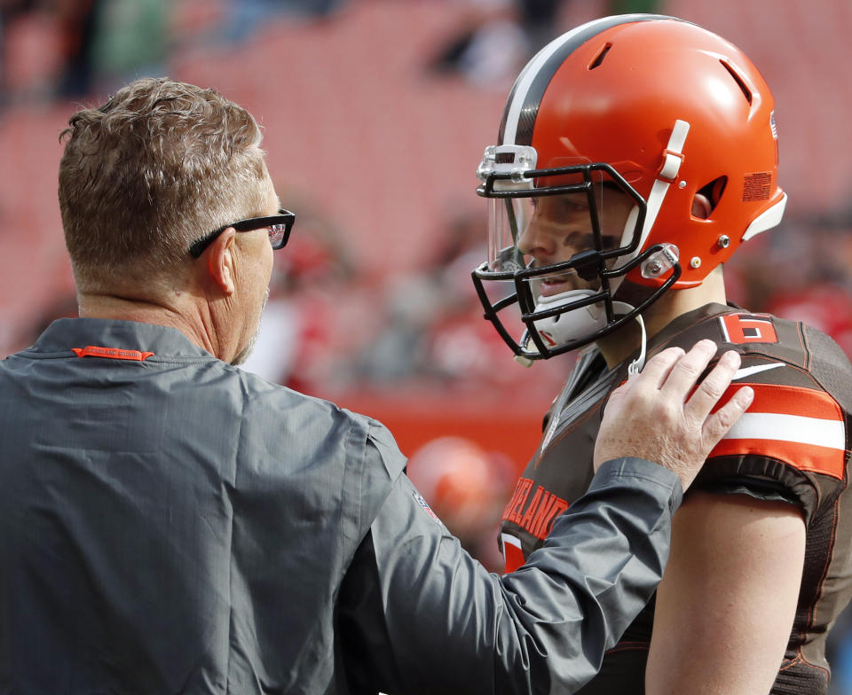 FILE - In this Sunday, Nov. 4, 2018, file photo, Cleveland Browns head coach Gregg Williams talks quarterback Baker Mayfield (6) before his first game as head coach against the Kansas City Chiefs in an NFL football game in Cleveland. Many teams think it's best to throw rookie QBs right into the fire to learn on the job. Others prefer to gradually work them into the offense. Then, there are some who believe it's more beneficial to have them grab a cap and a clipboard and take it all in from the sideline. (Jeff Haynes/AP Images for Panini via AP, File)