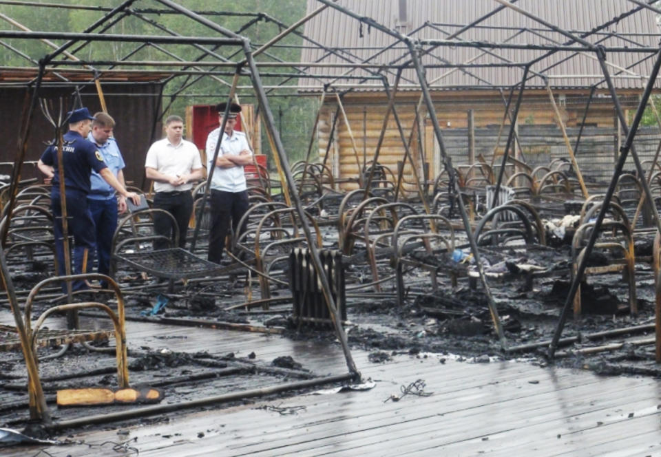 In this photo provided by Russian Emergency Situations Ministry for the Khabarovsk Region Press Service, officials inspect a tent camp after fire near Solnechny village, Khabarovsk Region, Russia, Thursday, June 27, 2019. Russian authorities say three children have died in a fire at the tent camp in a ski area in the Khabarovsk region about 6,000 kilometers (3.700 miles) east of Moscow, that housed some 189 people at the time of the fire, news reports said. (Ministry of Emergency Situations for Khabarovsk Region Press Service via AP)