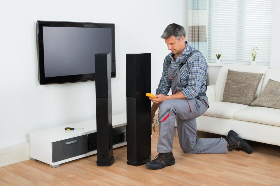 Full length of technician checking TV speaker with multimeter at home