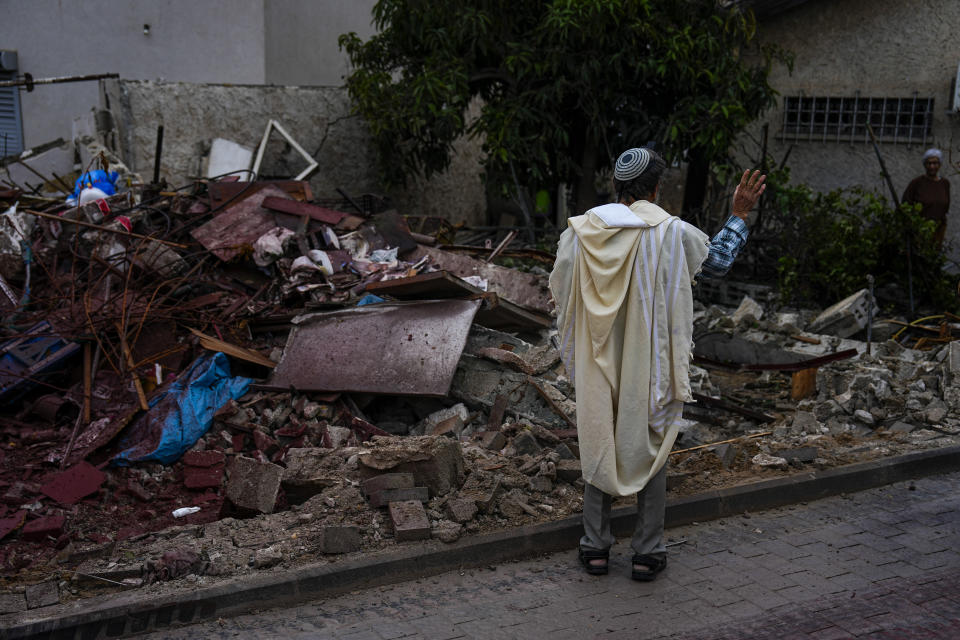 A man covered in a prayer shawl holds a holy book as he stands by a structure destroyed by a rocket fired Wednesday night from the Gaza Strip by Palestinian militants, in Ashkelon, Israel, May 11, 2023. / Credit: Ariel Schalit/AP