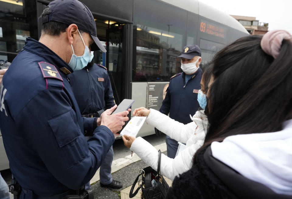 Policemen check the green health pass of public transportation passengers in Rome, Monday, Dec. 6, 2021, on the first day a super green health pass went into effect. Italian police can check whether diners in restaurants or bars have a "super" green health pass certifying that they are either vaccinated or have recently recovered from the virus. (AP Photo/Andrew Medichini)