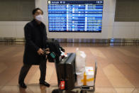 A flight passenger walks past a screen showing arrival schedules written in Chinese and English at the Haneda International Airport in Tokyo, Saturday, Jan. 14, 2023. A hoped-for boom in Chinese tourism in Asia over next week’s Lunar New Year holidays looks set to be more of a blip as most travelers opt to stay inside China if they go anywhere. (AP Photo/Hiro Komae)