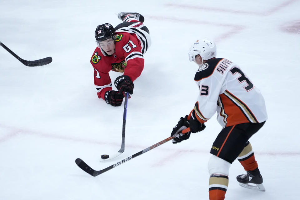 Chicago Blackhawks' Ian Mitchell (51) dives for a loose puck as Anaheim Ducks' Jakob Silfverberg skates nearby during the third period of an NHL hockey game Tuesday, Feb. 7, 2023, in Chicago. The Ducks won in overtime 3-2. (AP Photo/Charles Rex Arbogast)