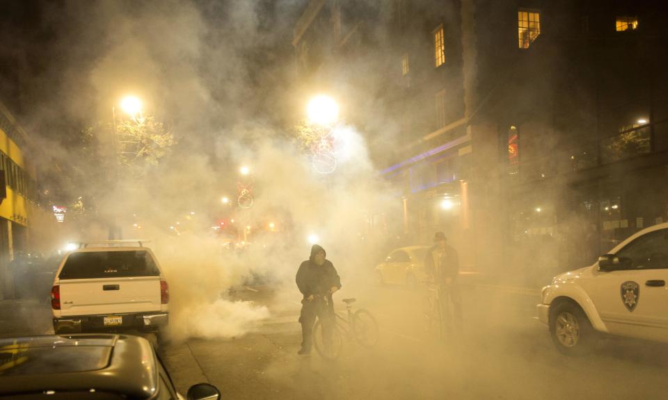 A man in a mask walks through teargas as police disperse protesters during a protest against police violence in the U.S., in Berkeley, California