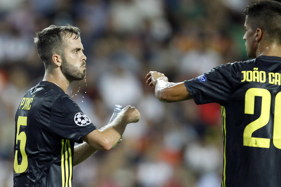 Juventus midfielder Miralem Pjanic, left, is congratulated by teammate Joao Cancelo after scoring on a penalty his side's opening goal during the Champions League, group H soccer match between Valencia and Juventus, at the Mestalla stadium in Valencia, Spain, Wednesday, Sept. 19, 2018. (AP Photo/Alberto Saiz)