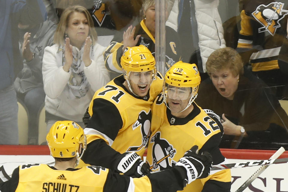Fans celebrate behind Pittsburgh Penguins' Evgeni Malkin (71) and Justin Schultz (4) as they greet Patrick Marleau (12) who scored against the Carolina Hurricanes during the first period of an NHL hockey game, Sunday, March 8, 2020, in Pittsburgh. (AP Photo/Keith Srakocic)
