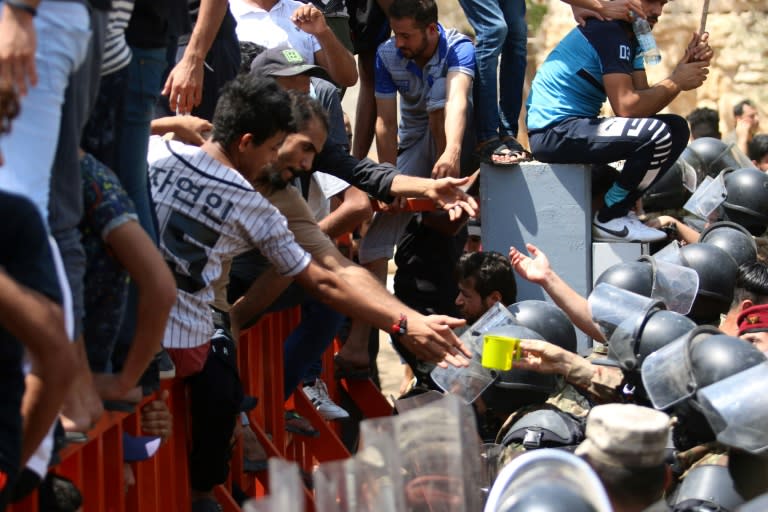 A member of the Iraqi security forces receives water from a protester in the southern Iraqi city of Basra on July 15, 2018