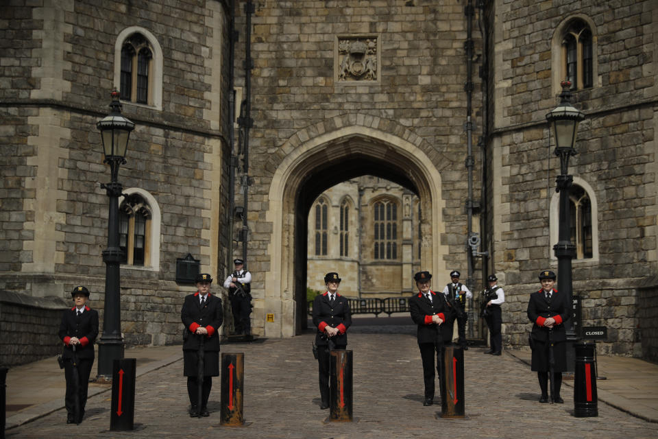 Wardens stand lined up, with police officers standing guard behind them outside the King Henry VIII Gate of Windsor Castle, in Windsor, England, Wednesday, April 14, 2021. Britain's Prince Philip, husband of Queen Elizabeth II, died Friday April 9 aged 99. His funeral service will take place on Saturday at Windsor Castle. (AP Photo/Matt Dunham)