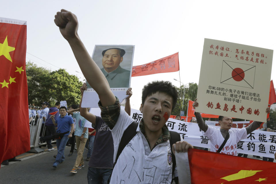 Chinese protesters march with banners declaring Diaoyu Islands, known as Senkaku to Japanese, belongs to China and a portrait of former Chinese leader Mao Zedong near the Japanese Embassy in Beijing, China, Sunday, Sept. 16, 2012. (AP Photo/Ng Han Guan)