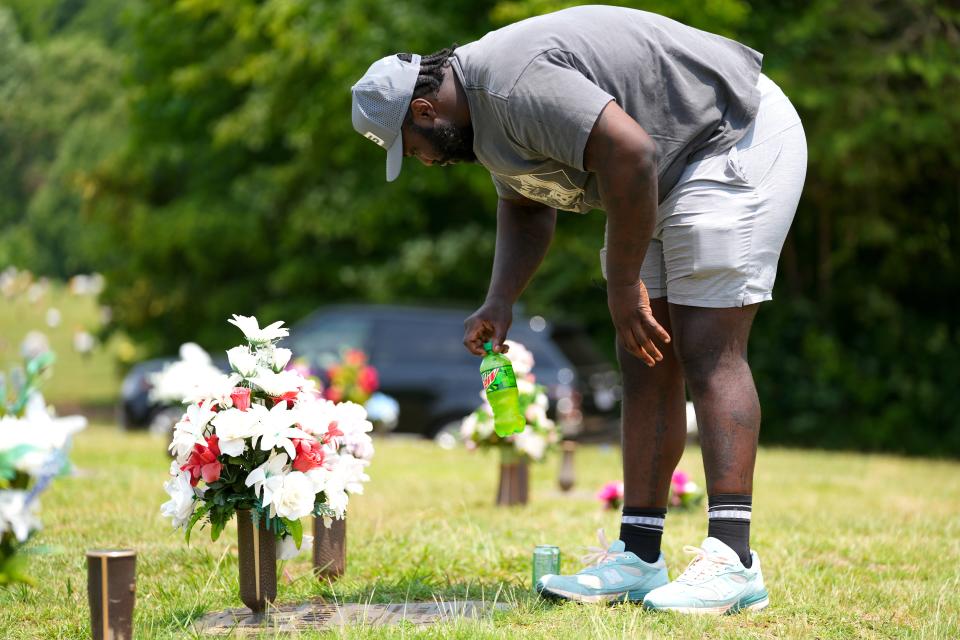 Cincinnati Bengals defensive tackle DJ Reader places a bottle of Mountain Dew on his dad’s, David Reader, gravesite, Friday, June 16, 2023, in Greensboro, N.C. Mountain Dew was David Reader’s favorite drink, and DJ always brings one with him whenever he visits.