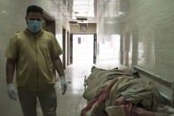 CORRECTS NAME OF PHOTOGRAPHER FROM MYSTYSLAV CHERNOV TO BALINT SZLANKO. A medical technician stands next to a dead body outside the refrigerator unit in Qayara hospital 35 miles south of Mosul. The hospital receives so many corpses from Mosul, where fighting continues between Iraqi forces and Islamic State militants, that sometimes they do not fit in the morgue and are left in the corridors. (AP Photo/Balint Szlanko)