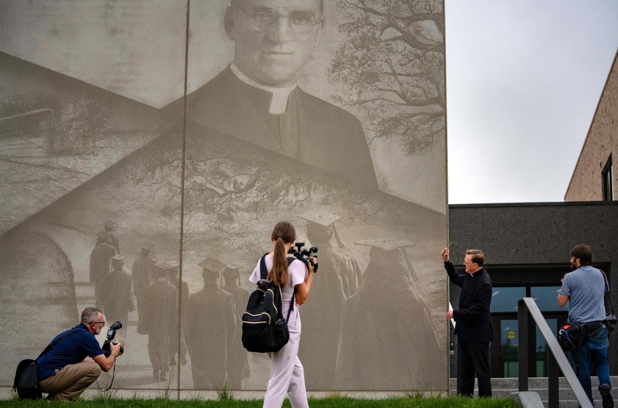 The Rev. Steven Boes sprinkles holy water on a mural featuring the face of Boys Town founder Edward J. Flanagan, in front of the new Boys Town Education Center on Thursday, Aug. 3, 2023.
