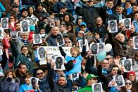 People hold flyers depicting Napoli's defender Kalidou Koulibaly before an Italian Serie A football match against Carpi on February 7, 2016 at the San Paolo stadium in Naples