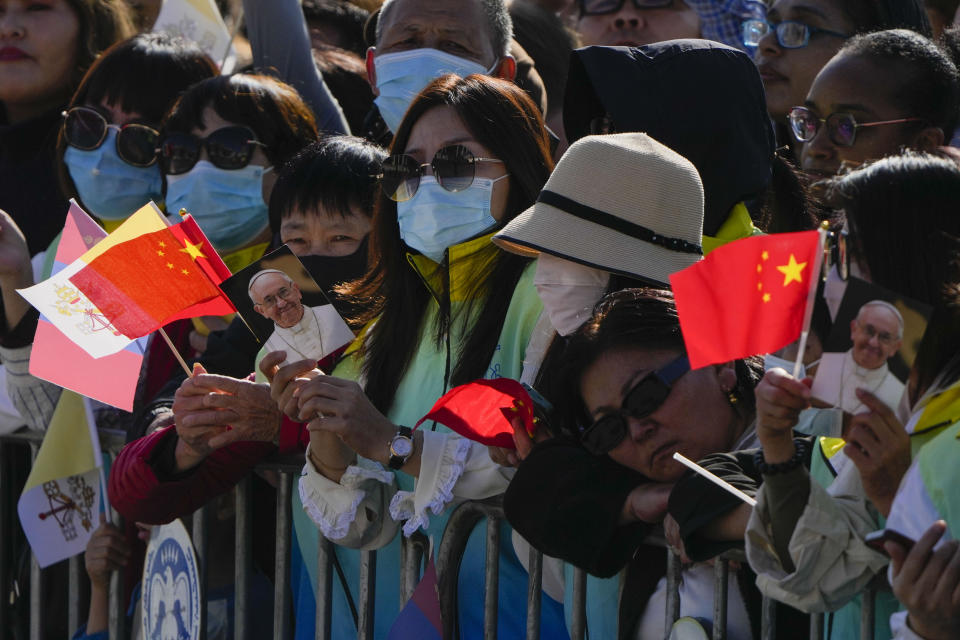 People hold pictures of Pope Francis with the national flags of the People's Republic of China and of the Vatican as they wait for Mongolian President Ukhnaagin Khurelsukh, and Pope Francis to meet, Saturday, Sept. 2, 2023, in front of a gigantic statue of former Khagan of the Mongol Empire Genghis Khan in Sukhbaatar Square in Ulaanbaatar. Pope Francis arrived in Mongolia on Friday morning for a four-day visit to encourage one of the world's smallest and newest Catholic communities. (AP Photo/Ng Han Guan)