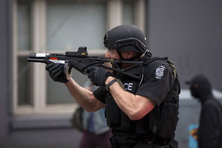 A police officer prepares to fire rubber bullets at demonstrators during an anti-capitalist protest in Seattle, Washington May 1, 2015. REUTERS/David Ryder