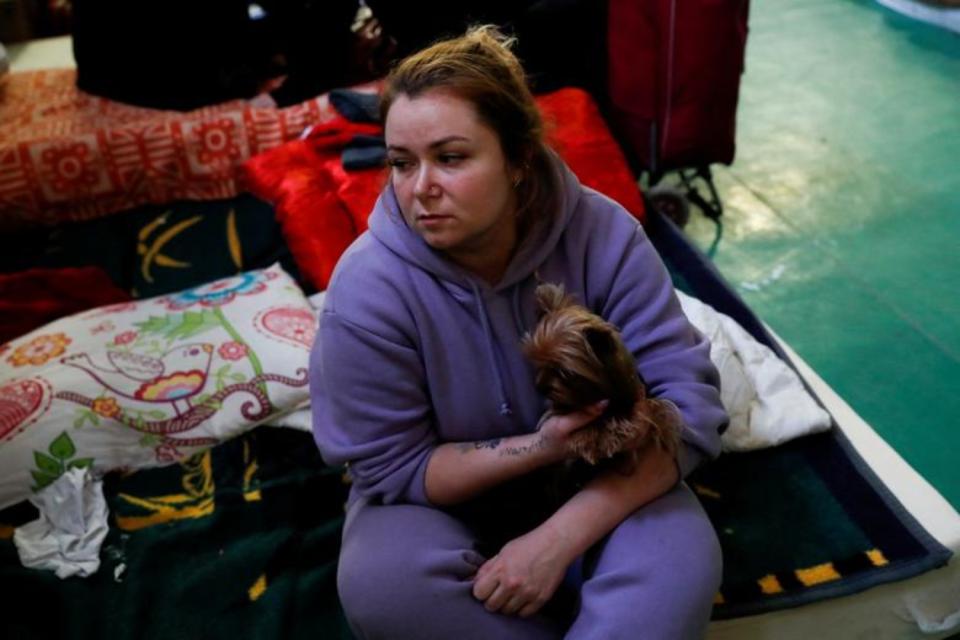<p>Una mujer descansa junto a sus pertenencias y a su perro en un centro temporal para refugiados habilitado en Tiszabecs, en Hungría. (Foto: Bernadett Szabo / Reuters).</p> 