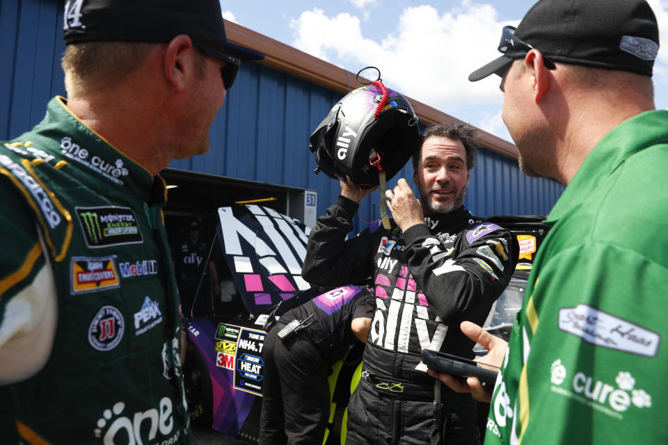 Jimmie Johnson, center, talks with Clint Bowyer, left, during practice for a NASCAR Cup Series auto race at Michigan International Speedway in Brooklyn, Mich., Saturday, Aug. 10, 2019. (AP Photo/Paul Sancya)