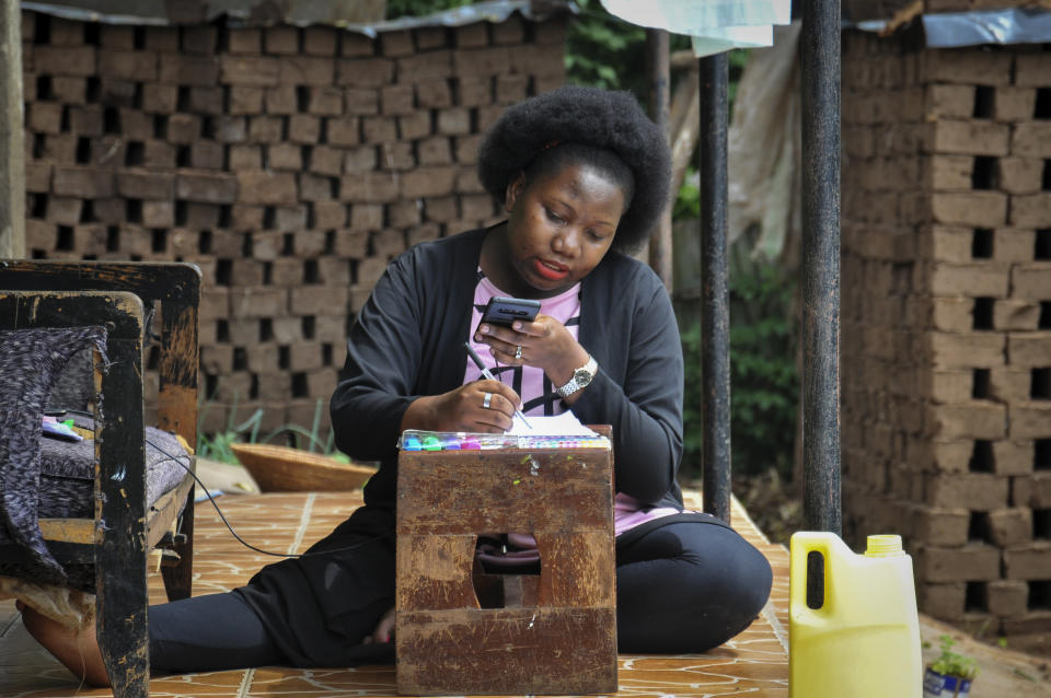 Stella Maris Basemera, a mathematics teacher who heads a Uganda-based group of tutors called Creative Learning Africa, writes work for students to complete which she sends them as a private tutor via WhatsApp, at her home just outside Kampala, Uganda Tuesday, July 7, 2020. The options for African students eager to keep studying while schools remain closed because of the coronavirus pandemic seems varied, but the reality for many is that they will fall behind and possibly drop out of school forever, worsening inequality on an already unequal continent. (AP Photo/Ronald Kabuubi)