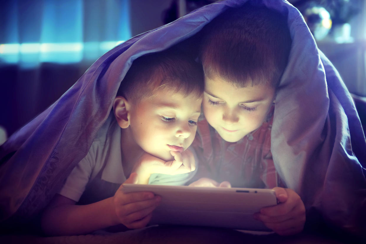 Brothers with tablet computer in a dark room