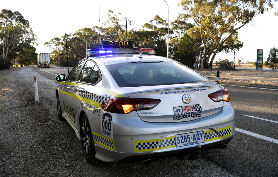 A police car is seen whilst motorists fill out paperwork for police as they cross back into South Australia from Victoria during the coronavirus disease (COVID-19) outbreak, in Bordertown, Australia, March 24, 2020. REUTERS/Tracey Nearmy