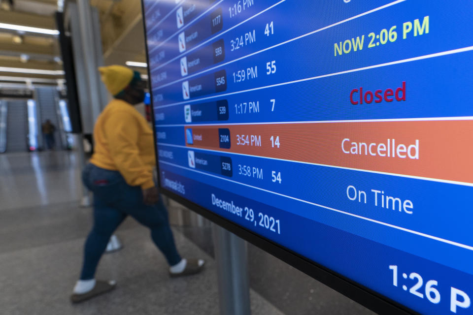 A flight shows cancelled on the departures board at Ronald Reagan Washington National Airport, Wednesday, Dec. 29, 2021, in Arlington, Va. Winter weather and crew members infected with COVID-19 have forced airlines to spike thousands of U.S. flights over the past week, complicating travel plans for many people during the busy holiday season. It’s not clear when travel will return to normal, but airlines say a recent move by U.S. public health officials should help get workers back sooner. (AP Photo/Alex Brandon)