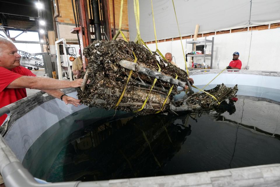 Wayne Lusardi, Michigan's state maritime archaeologist with the Department of Natural Resources helps guide the 1,200-pound mussel-encrusted engine from a P-39 World War II-era fighter plane flown by a member of the famed Tuskegee airmen into a chemical solution, Thursday, Aug. 17, 2023, at the Tuskegee Airmen National Historical Museum in Detroit.