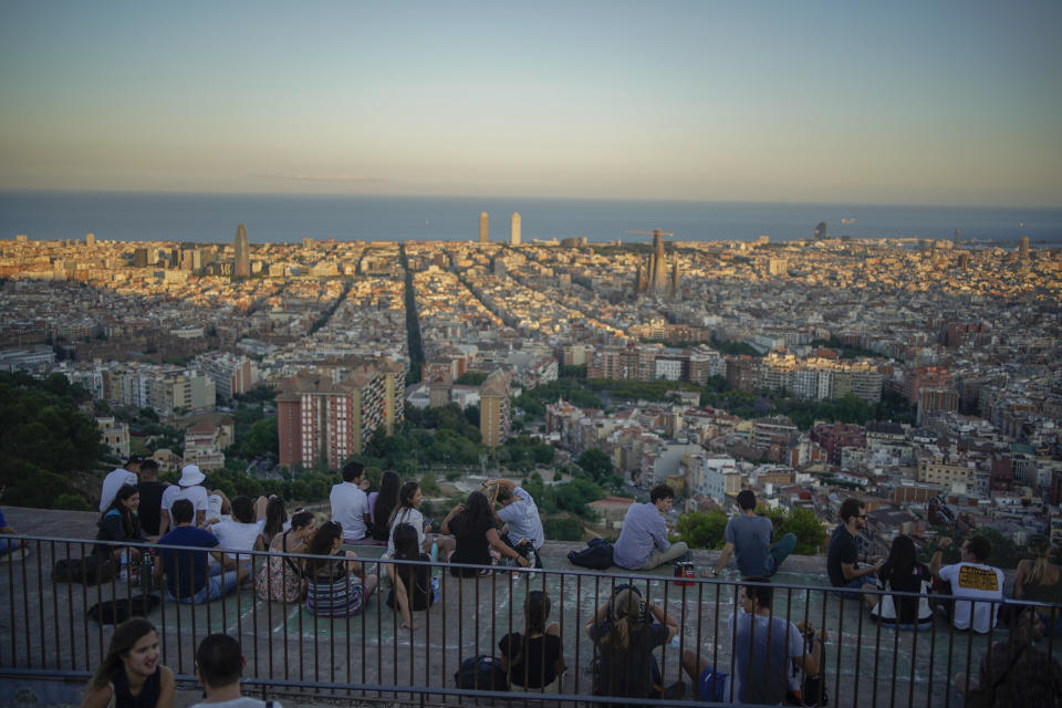 People sit at a panoramic vantage point overlooking the city of Barcelona, Spain, Monday, June 21, 2021. (AP Photo/Joan Mateu)