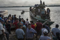 Passengers arrive in a public taxi boat to the Shipibo Indigenous community of Pucallpa, located along the Ucayali River in the Amazonian rainforest of eastern Peru, Thursday, Sept. 3, 2020, amid the new coronavirus pandemic. Transportation is one of the biggest hurdles in treating indigenous groups, some of which can only be reached by helicopter or an eight-hour boat ride. (AP Photo/Rodrigo Abd)