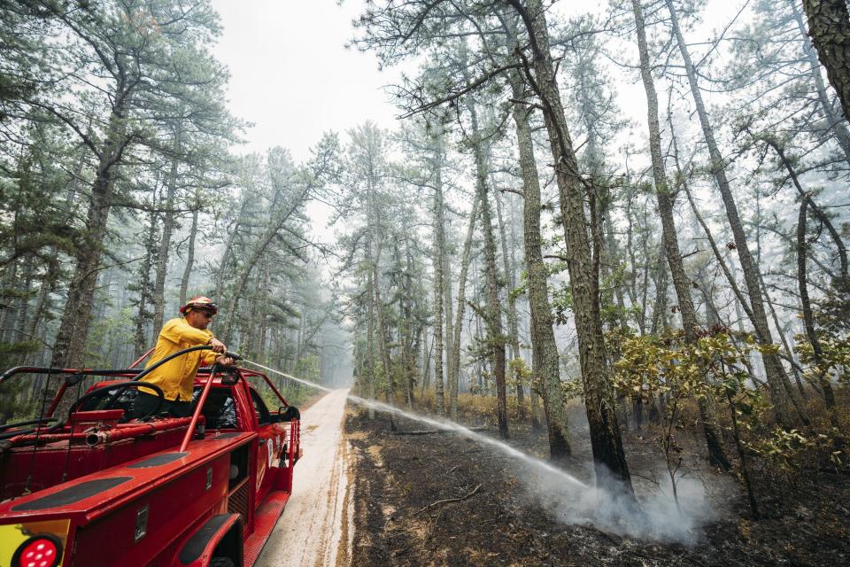 This Friday, July 5, 2024 image provided by the New Jersey Department of Environmental Protection shows members of the New Jersey Forest Fire Service battling a forest fire in Tabernacle, N.J. The fire had burned 4,000 acres and was 75% contained as of Monday July 8. (New Jersey Department of Environmental Protection via AP)