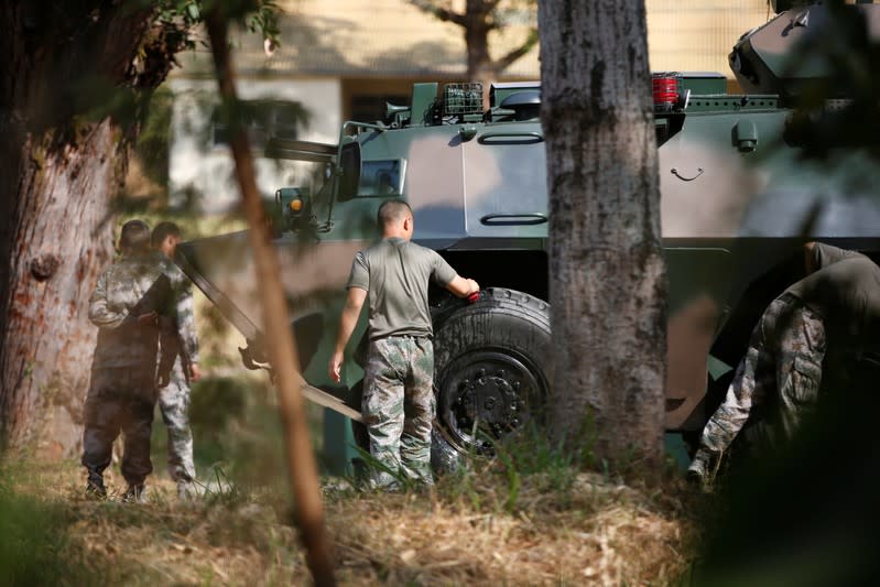 People's Liberation Army (PLA) troops in t-shirts and khaki trousers clean and service an armoured personnel carrier in the Tam Mei barracks in Hong Kong