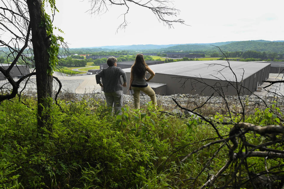 People look out over a Jack Daniels barrelhouse complex, as they stand on a landowners property that borders the facility Wednesday, June 14, 2023, in Mulberry, Tenn. A destructive and unsightly black fungus which feeds on ethanol emitted by whiskey barrels has been found growing on property near the barrelhouses. (AP Photo/John Amis)